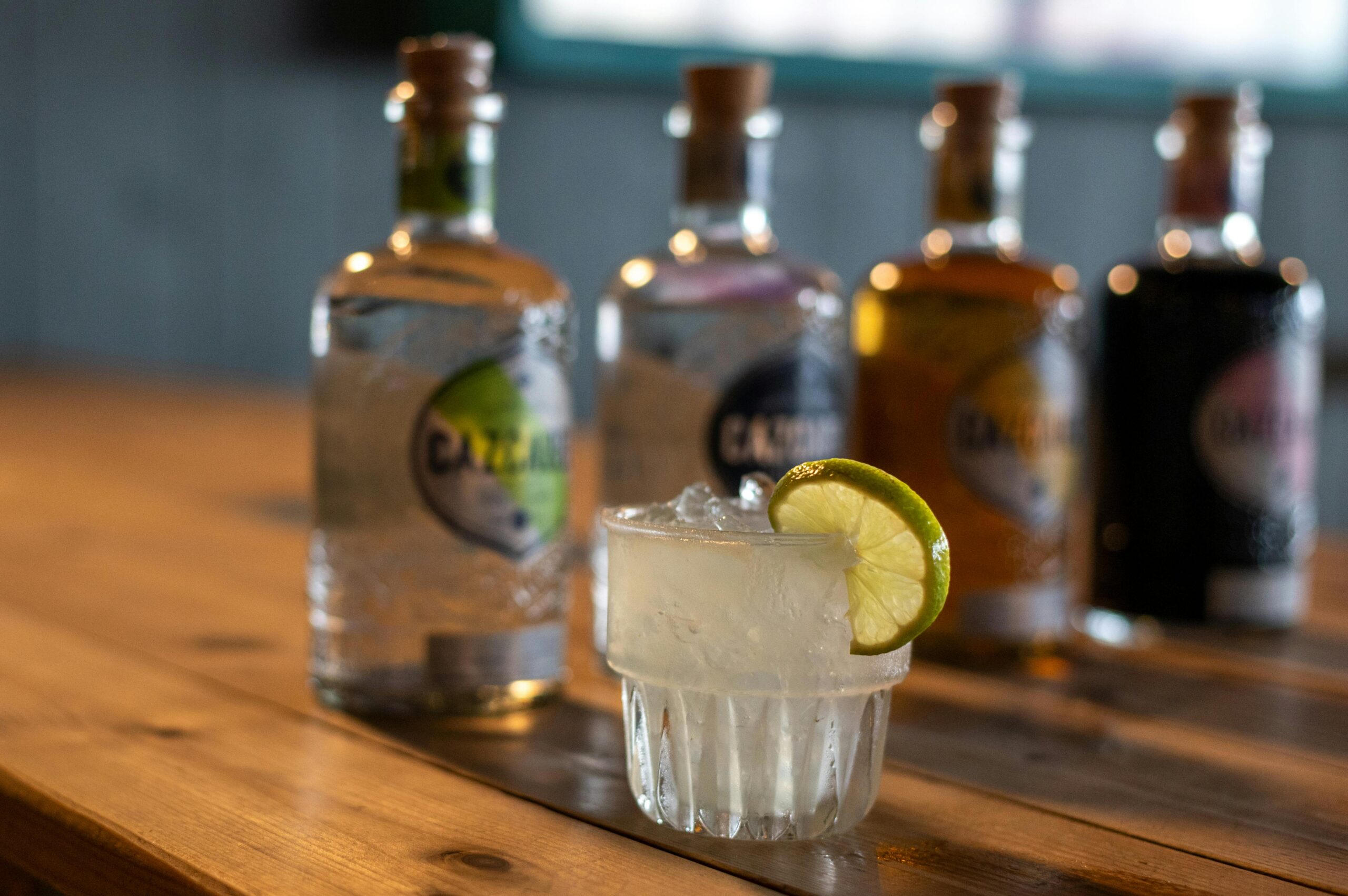 Carte A citrus-enhanced cocktail with lime and ice, spotlighted in a stylish indoor setting with spirits in the background.