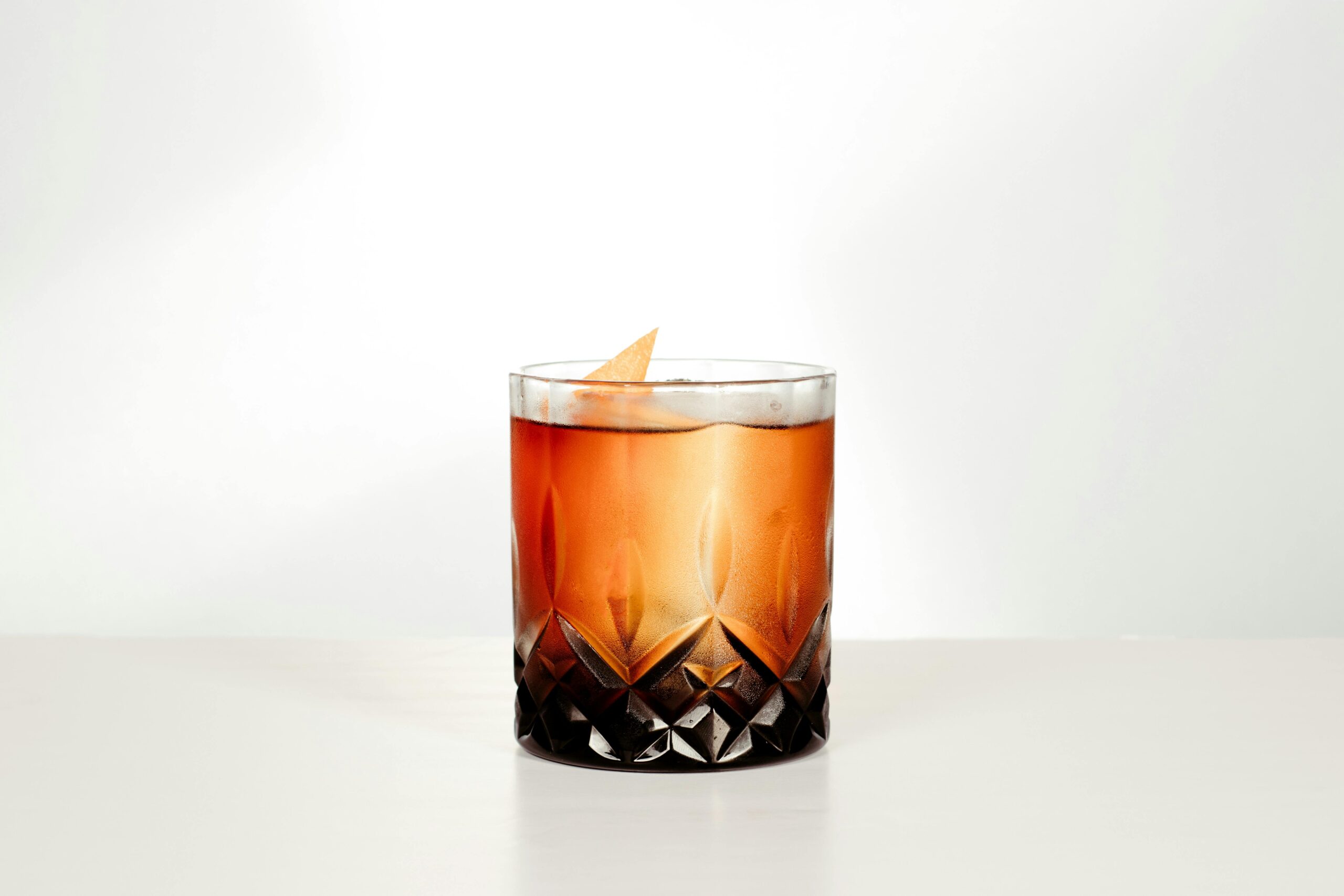 Carte A sophisticated whiskey cocktail with an orange twist served in a crystal glass, perfect for a classy setting.