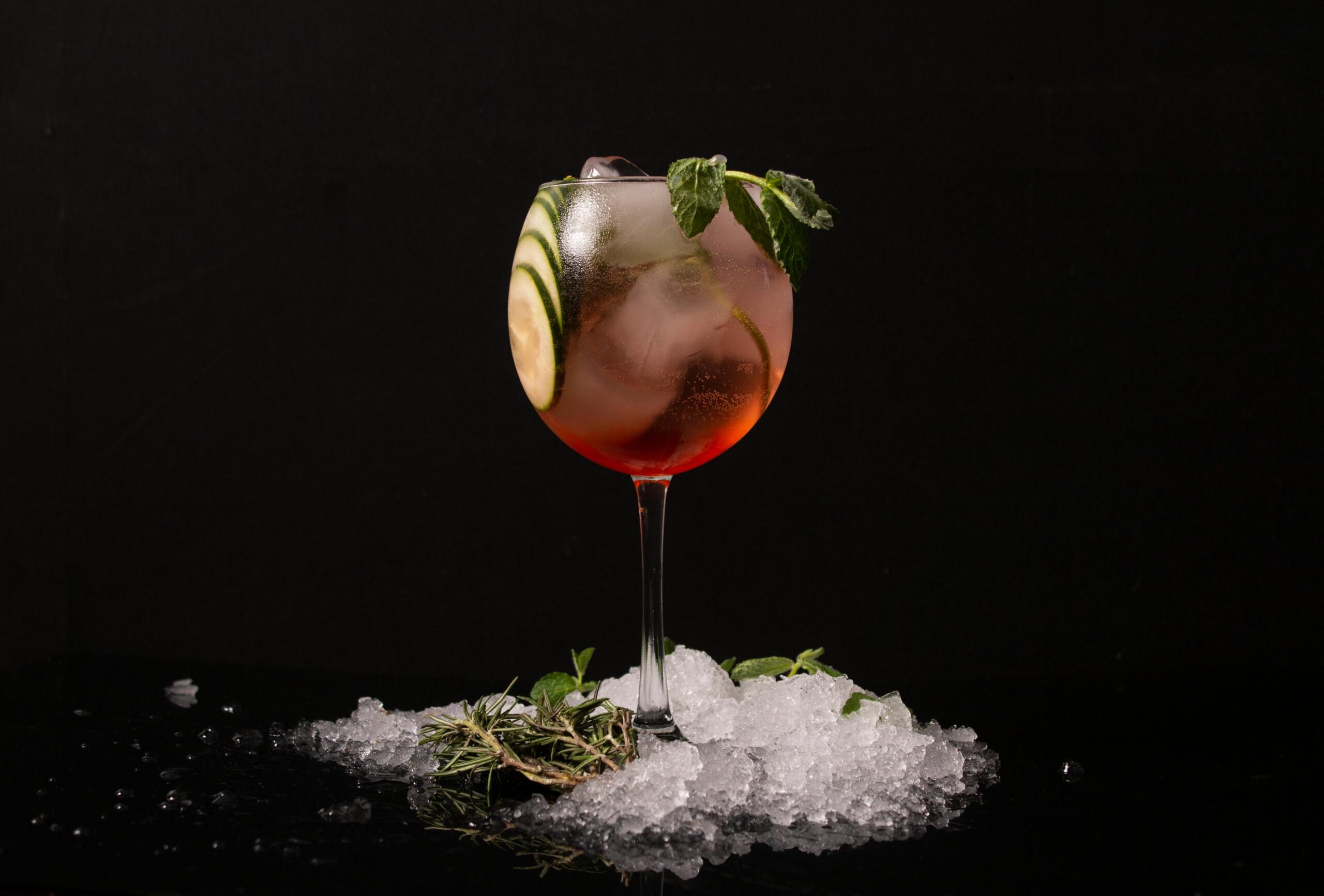 Carte A refreshing cocktail in a glass with cucumber and mint garnish, surrounded by ice.